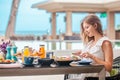 Woman on breakfast near swimming pool in luxurious tropical resort. Table full of various food and drinks on, healthy Royalty Free Stock Photo