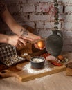 Woman breaks chicken egg into flour on wooden board.