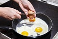 Woman breaks an egg in fried eggs