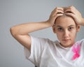 Woman with breast cancer holding her head on white background. Royalty Free Stock Photo