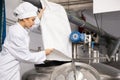 Woman brewer pouring beer yeast into tank