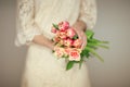 Woman bride hands holding spring flowers tulips and roses, boho wedding dress