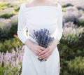 Woman bride, holding in hands bouquet of lavender flowers on background of field, close-up Royalty Free Stock Photo