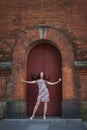 A woman in a bright dress stands near an old building and laughs Royalty Free Stock Photo
