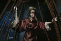 woman with bright makeup in a steampunk scenery holds with her hands for red chains.