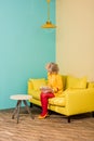 woman in bright retro clothing with golden fish in aquarium resting on sofa at colorful apartment doll Royalty Free Stock Photo