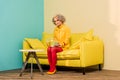 woman in bright retro clothing with golden fish in aquarium on sofa at colorful apartment, doll Royalty Free Stock Photo