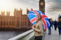 Woman with a British flag umbrella stands in front of the Big Ben Tower in London, United Kingdom Royalty Free Stock Photo