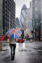 A woman with a british flag umbrella walks in the City of London during a rainy day