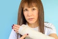 Woman with broken arm bone in cast, plastered hand on blue background. Royalty Free Stock Photo