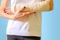 Woman with broken arm bone in cast, plastered hand on blue background. Royalty Free Stock Photo