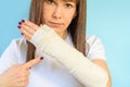 Woman with broken arm bone in cast, plastered hand on blue background. Royalty Free Stock Photo