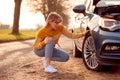 Woman Broken Down On Country Road Checking Car Tyre For Puncture Royalty Free Stock Photo