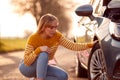 Woman Broken Down On Country Road Checking Car Tyre For Puncture Royalty Free Stock Photo