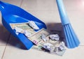 Woman broom sweeps dollars in garbage scoop on floor background Royalty Free Stock Photo