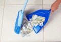 Woman broom sweeps dollars in garbage scoop on floor background