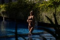 Woman in Brown Bikini with Crossed Arms in Shaded Pool