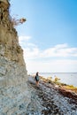 Woman with brown curly hair hiking by the Panga cliff in Saaremaa, Estonia during sunny day. The highest bedrock outcrop in
