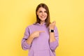 Woman with brown hair pointing finger on watch on her wrist looking at camera with toothy smile. Royalty Free Stock Photo