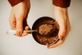 A woman in a brown jacket takes out a portion of fragrant crumbly cocoa powder from a jar with a beautiful silver teaspoon. The Royalty Free Stock Photo