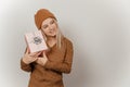 Woman in a brown sweater and hat holding a pink gift in her hands on a gray background Royalty Free Stock Photo