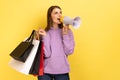 Woman with brown wavy hair holding shopping bags and megaphone, announcing sale and discount. Royalty Free Stock Photo