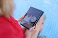 Woman is browsing web statistics using tablet while sitting on edge of swimming pool Royalty Free Stock Photo