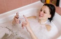 Woman bruenette chatting on mobile phone during bath at home.