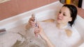 Woman bruenette chatting on mobile phone during bath at home.