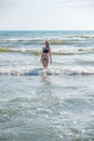 Woman bruenette with long hair in blue bikini going to swim in the wave`s sea. Front view.