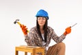 Woman, brunette builder with tools, looks seriously into camera on white background. Hammer. Space for an advertisment