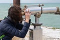 Woman brunette looking through coin operated binoculars at seaside ocean beach Royalty Free Stock Photo