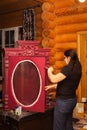 Woman with brush in hand painting door of wooden cupboard with carved ornaments in red color. Meticulous process of