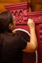 Woman with brush painting patterned cupboard with carved ornaments in red. Process of furniture patination. Eco-friendly Royalty Free Stock Photo