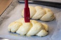 Woman with brush spreads easter braid with eggs milk glaze Royalty Free Stock Photo