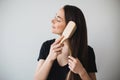 Woman brushes her long hair with wooden hairbrush