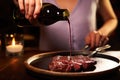woman brushing wine reduction on sizzling steak