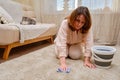 A woman with a bucket and a rag washes the carpet in the home living room Royalty Free Stock Photo