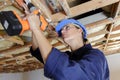 woman builder drilling hole in ceiling