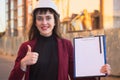 Woman builder holding blueprints, clipboard. Smiling architect girl in helmet at building background Royalty Free Stock Photo