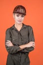 woman builder in protective helmet and boilersuit on orange background, engineering