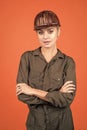 woman builder in protective helmet and boilersuit on orange background, engineering