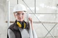 Woman builder work with the straightedge spirit level, wearing helmet, safety glasses and hearing protection headphones,