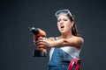 Woman builder worker with drill standing against grey background Royalty Free Stock Photo