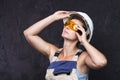 Woman builder worker in uniform with white helmet and protective construction glasses on black background. Woman in workwear