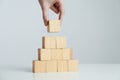 Woman building pyramid of blank wooden cubes on white table against light background, closeup. Space for text Royalty Free Stock Photo