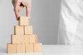 Woman building pyramid of blank cubes on white table against light background, closeup. Space for text Royalty Free Stock Photo