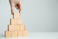 Woman building pyramid of blank wooden cubes on white table against light background, closeup. Space for text Royalty Free Stock Photo