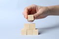Woman building pyramid of cubes on light background, closeup with space for text. Idea concept Royalty Free Stock Photo