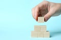 Woman building pyramid of cubes on light blue background, closeup with space for text. Idea concept Royalty Free Stock Photo